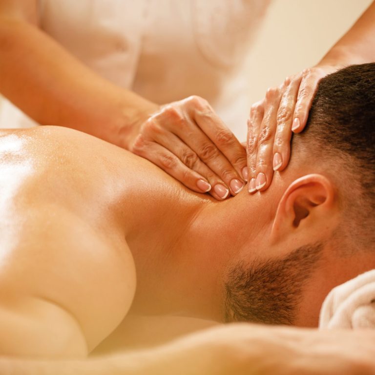 Close-up of therapist massaging man's neck during spa treatment.